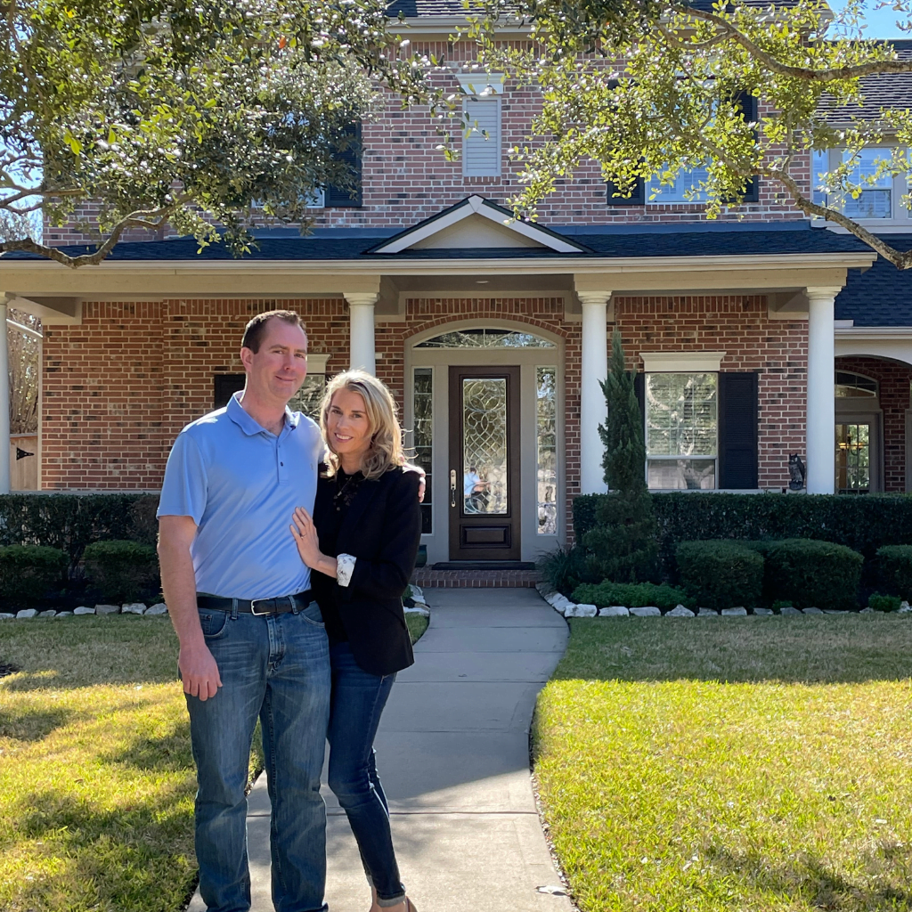 A man and woman standing in front of their home.