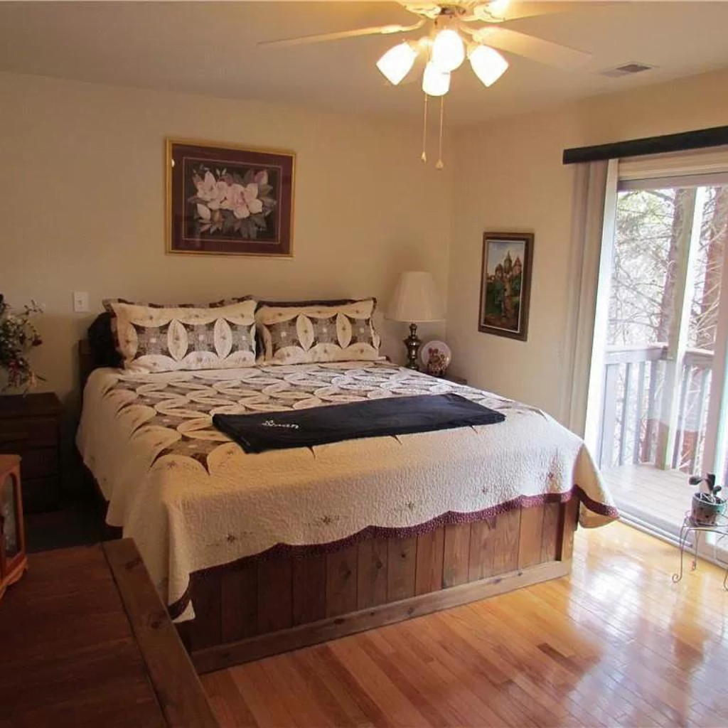A bedroom with hardwood floors and a sliding glass door.