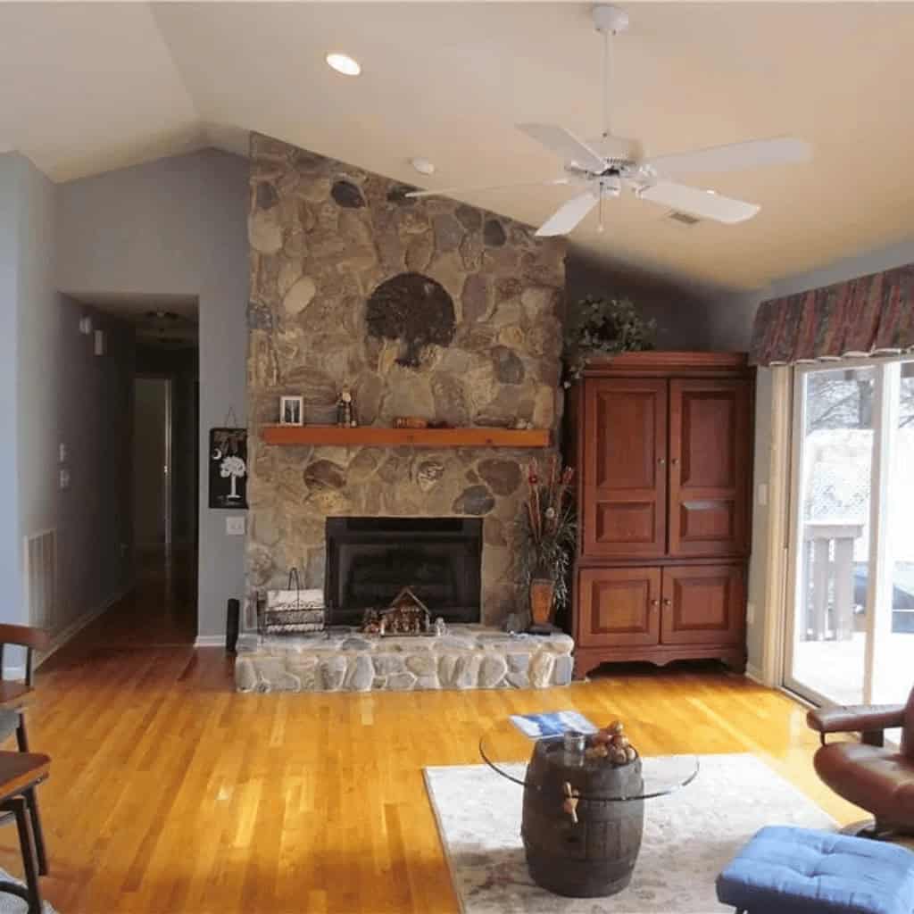 A living room with hardwood floors and a stone fireplace.