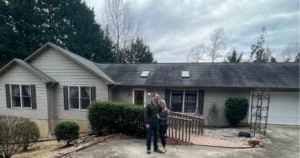Two people standing in front of a house.
