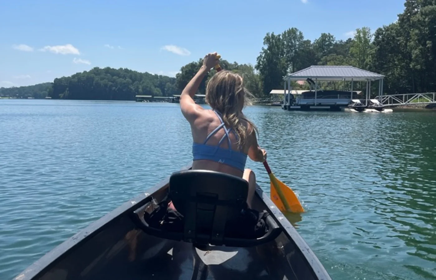 A woman paddles a canoe on a lake.